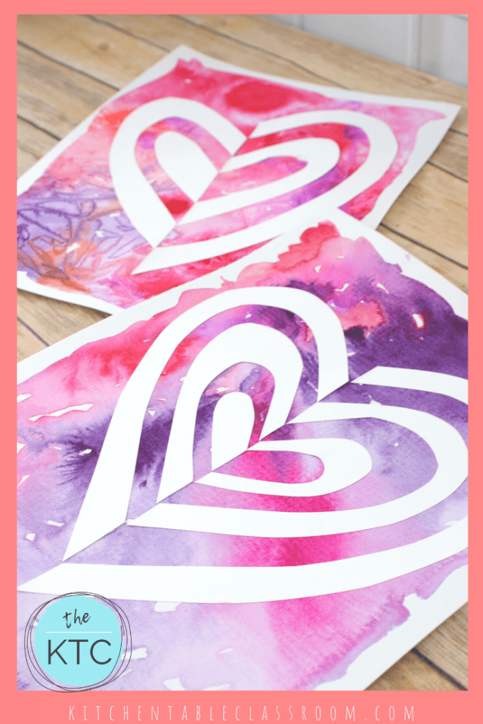cut paper heart art with pink and purple watercolor background
